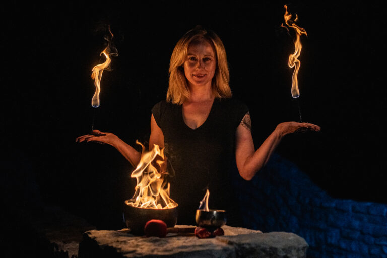 Casey ABlaze holds palm torches in front of a flaming singing bowl
